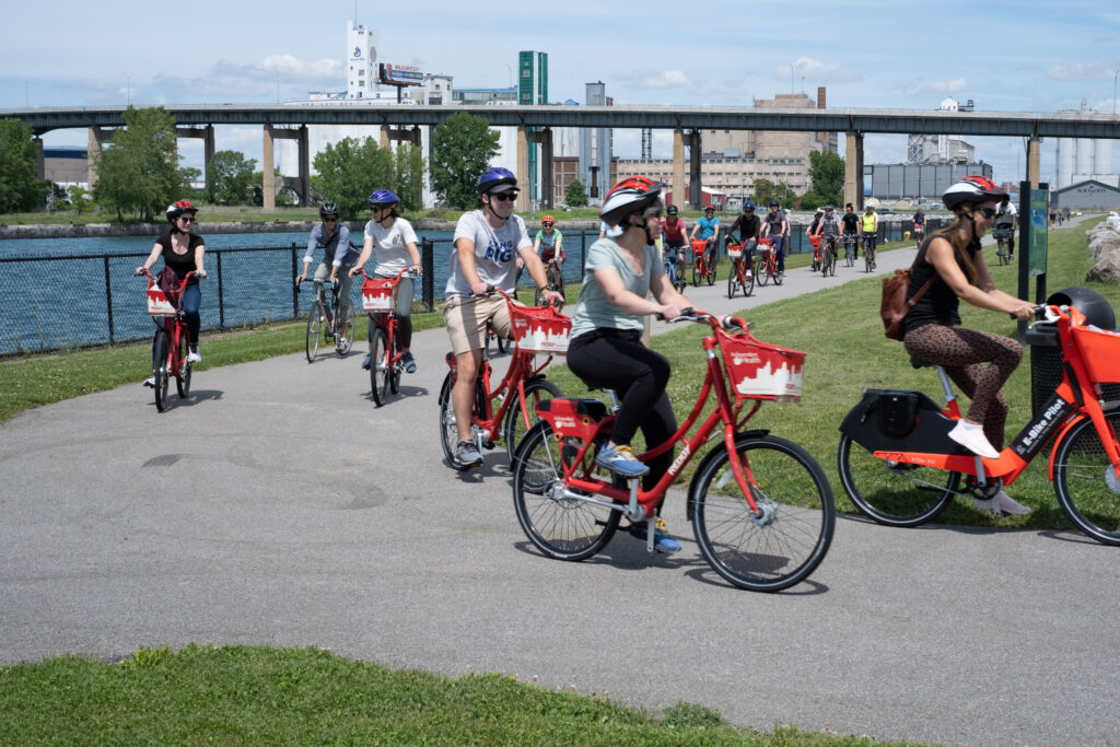 A group of bike riders on a trail near the river in Buffalo