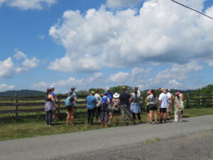 A group stands near a fence on a farm in NJ with large clouds above them