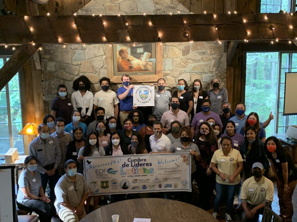 A large group of leaders poses for a photo with an oversize check in front of them.